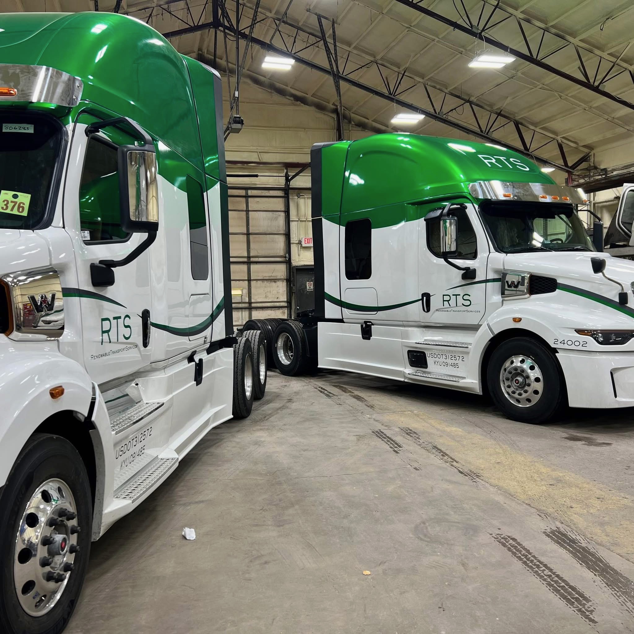 Two RTS green and white tractors parked side by side in the maintenance shop